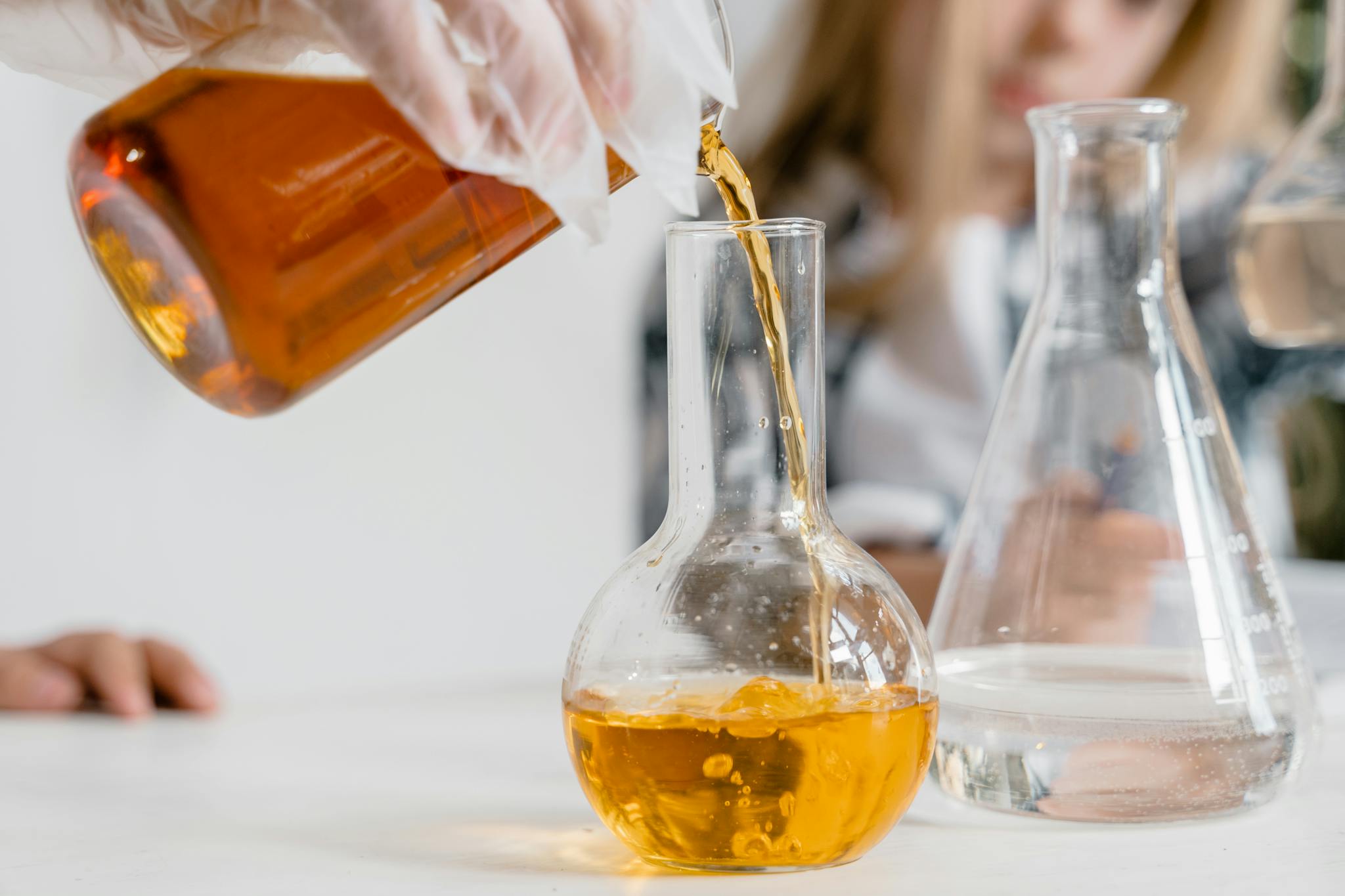 A curious child pours liquid into a flask during a science experiment indoors.