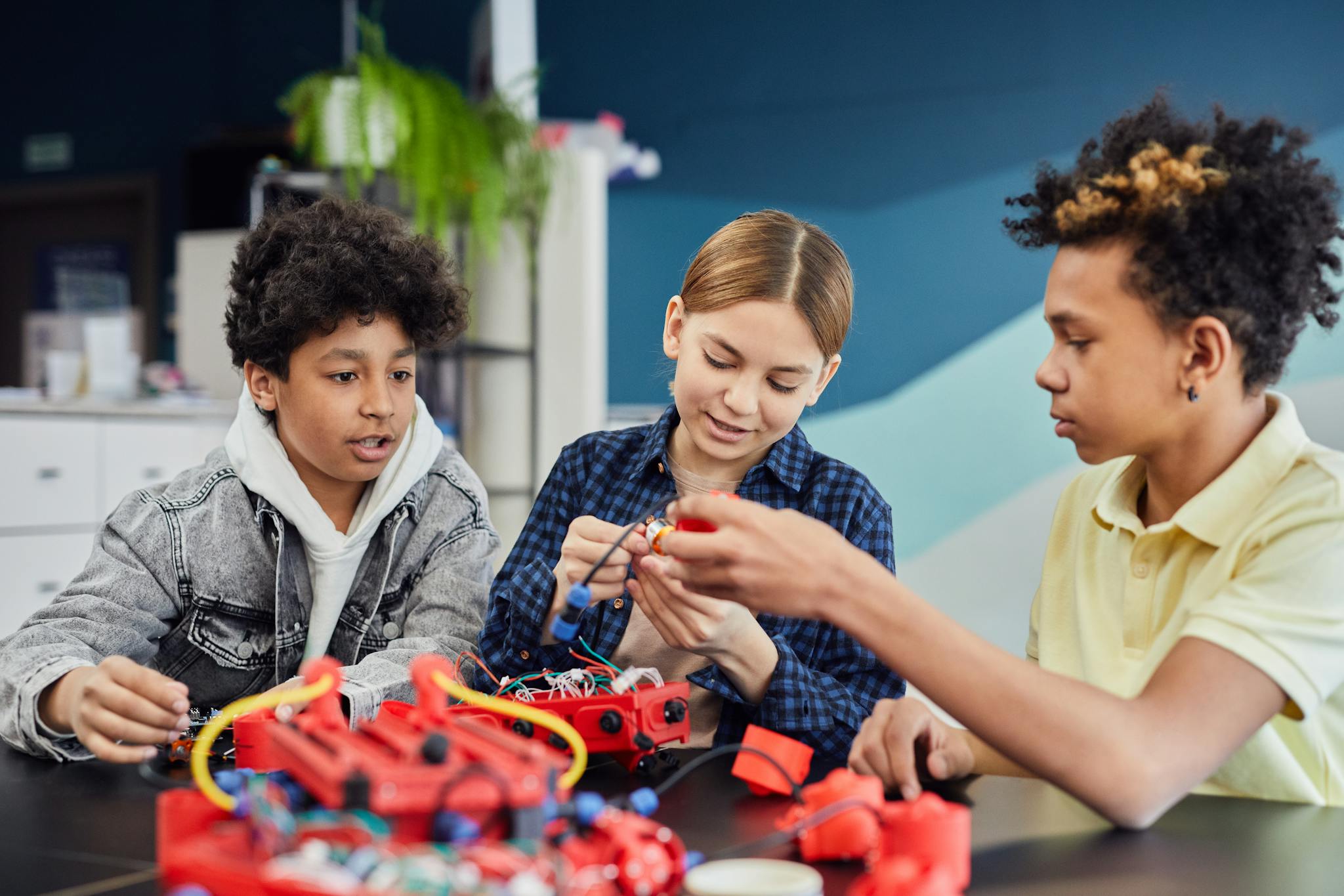 Diverse teens working together on a robotics project, showcasing teamwork and learning.